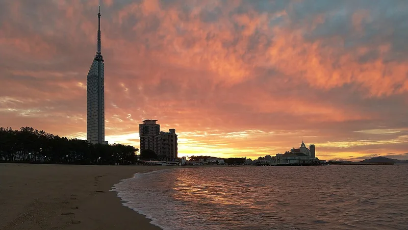 Orange sunset above Fukuoka Tower and the shore at Momochi Seaside Park