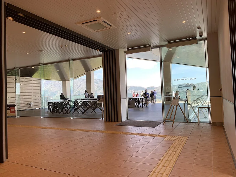 The indoor lounge opening onto the outdoor deck at cu-mo Hakone in Sounzan Station