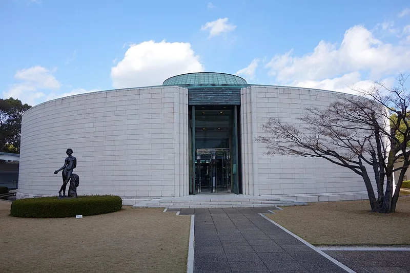 The curved white exterior of Hiroshima Museum of Art beneath a blue sky