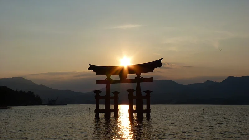 Sunset over the great torii gate of Itsukushima Shrine, reflected in the water off Miyajima