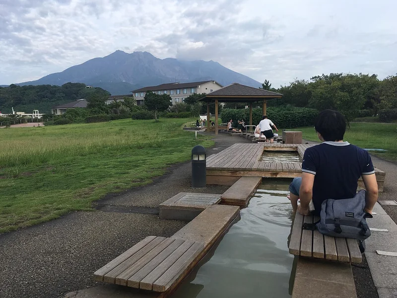 Visitors relaxing at the long footbath in Sakurajima Yogan Nagisa Park