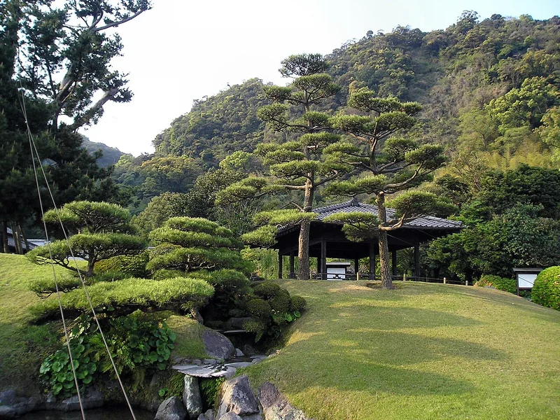 Shaped pine trees, lawn and a traditional pavilion in the gardens of Sengan-en