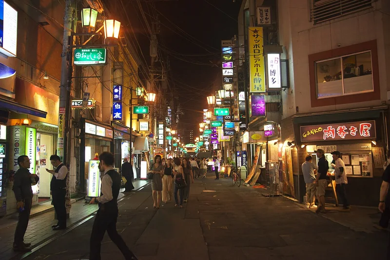 People and illuminated restaurant signs on a Tenmonkan street at night