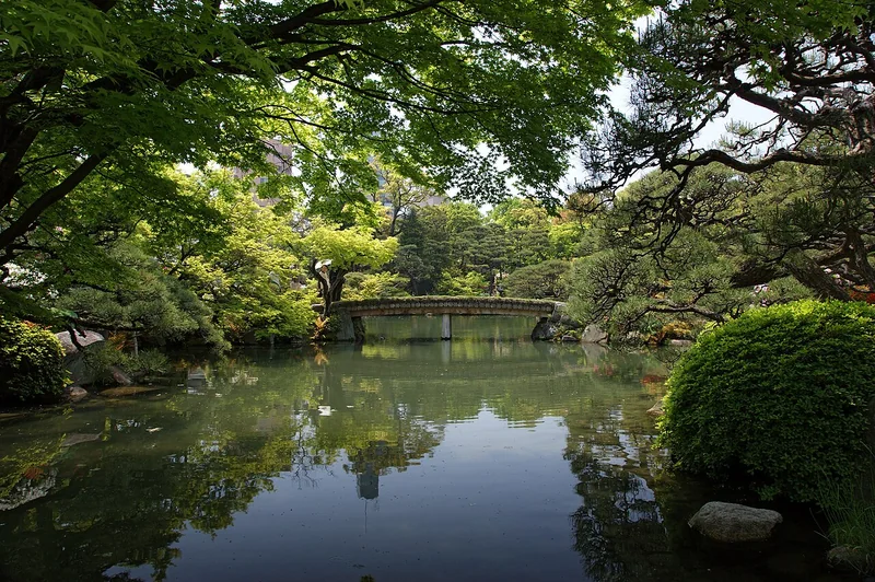 Green trees reflected in the pond at Sorakuen Garden