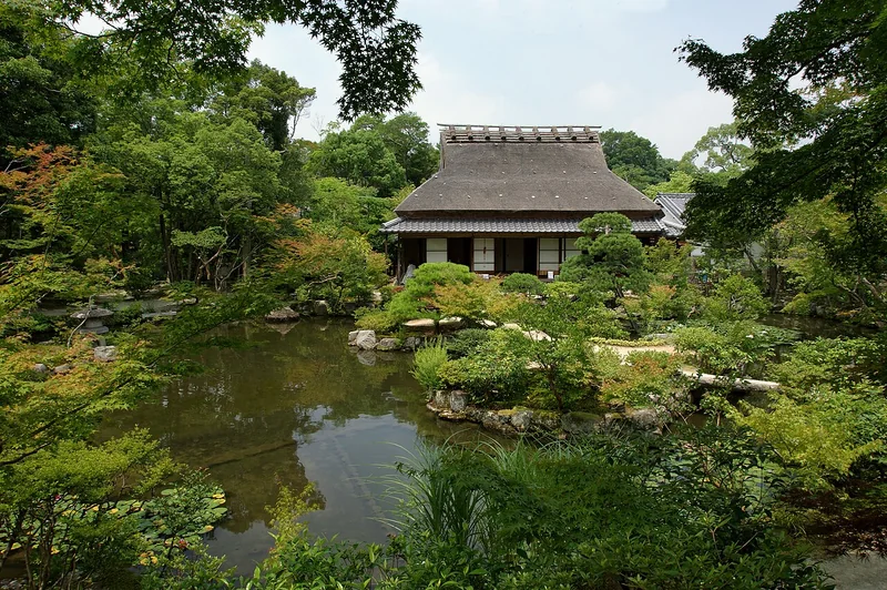 A traditional building and green garden reflected in a pond at Isuien
