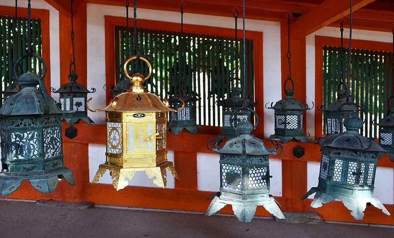 Hanging bronze lanterns along a vermilion corridor at Kasuga Taisha