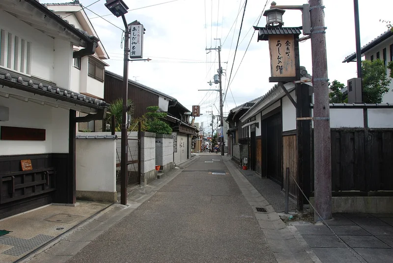Traditional wooden houses and a hanging lantern on a narrow Naramachi street