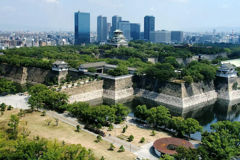 Osaka Castle rising above its moats and green park, with the city skyline beyond