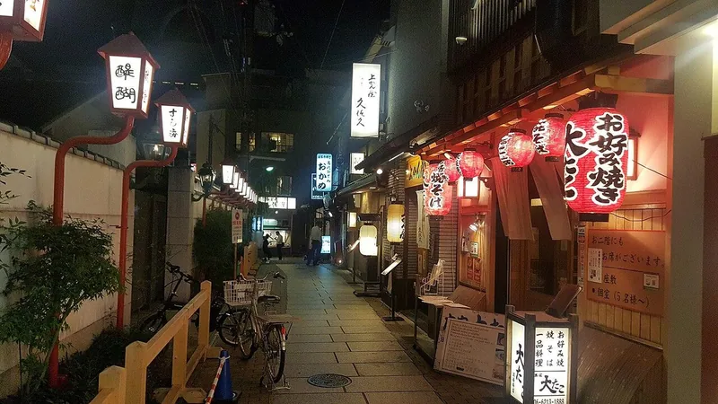 Warm lanterns and restaurant entrances along Hozenji Yokocho at night