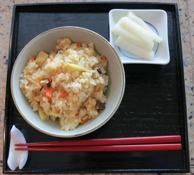 Seasoned rice with mixed ingredients, accompanied by pickles.