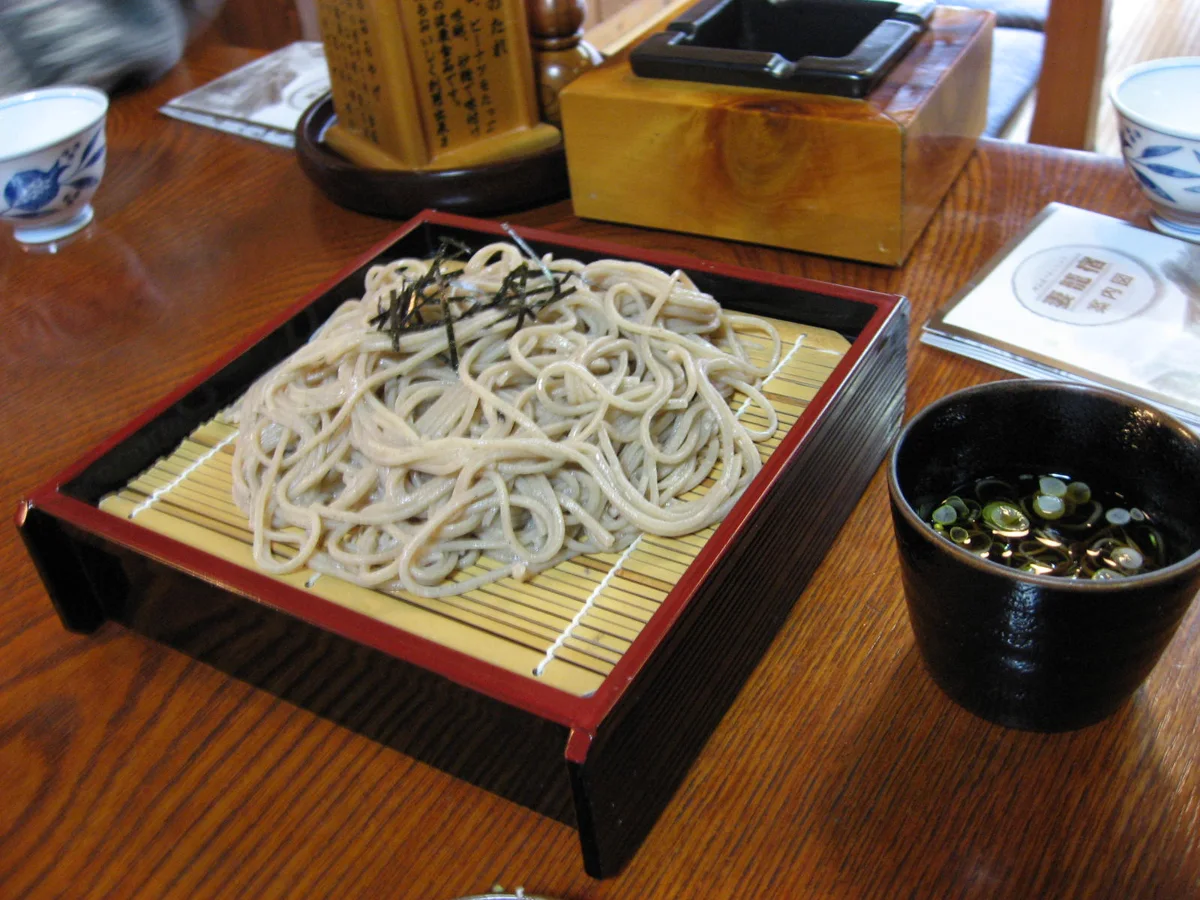 Cold soba noodles on a tray with dipping sauce.