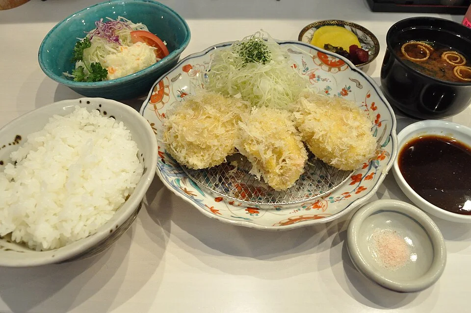 A pork cutlet set with rice, soup and accompaniments.