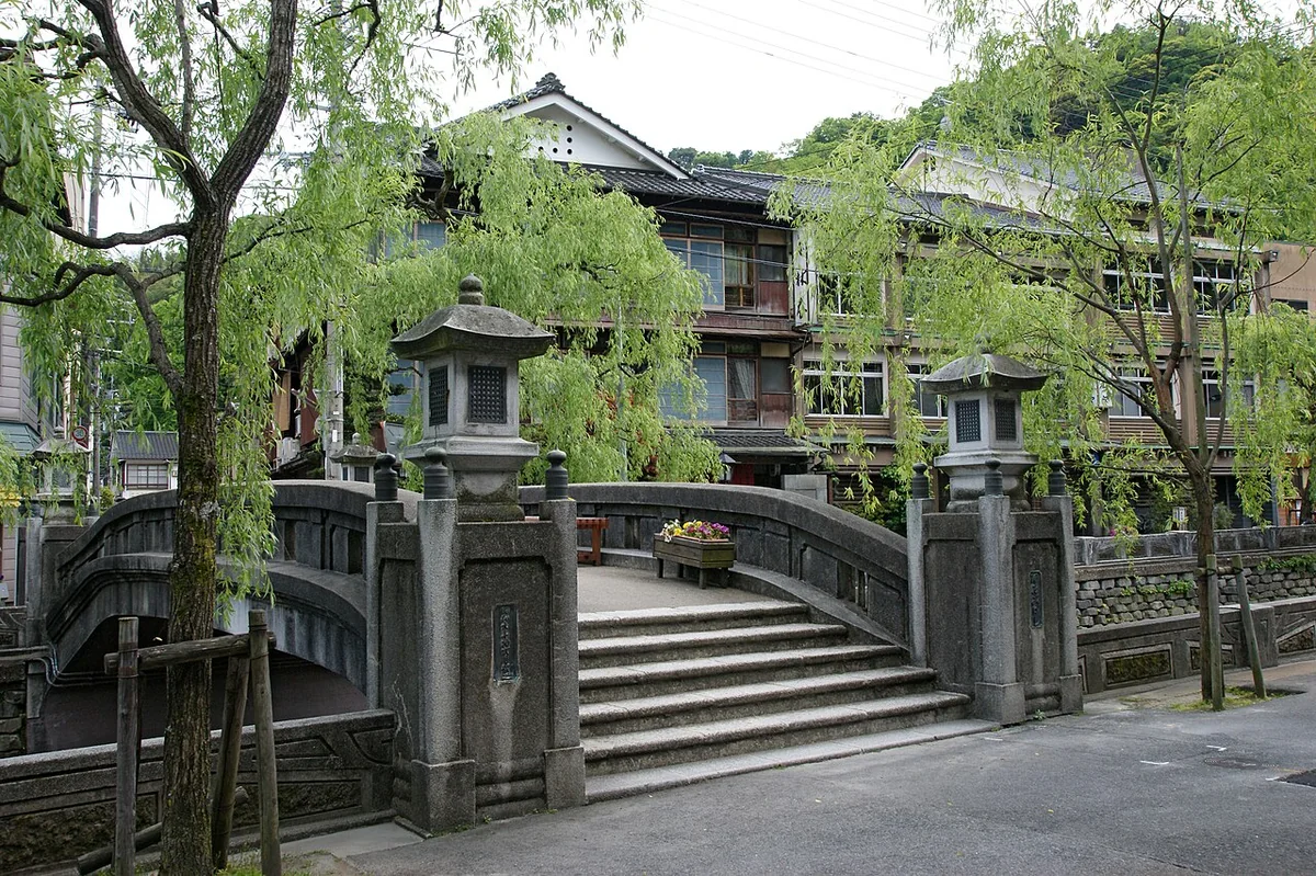 Willow trees and a stone bridge beside the canal in Kinosaki Onsen