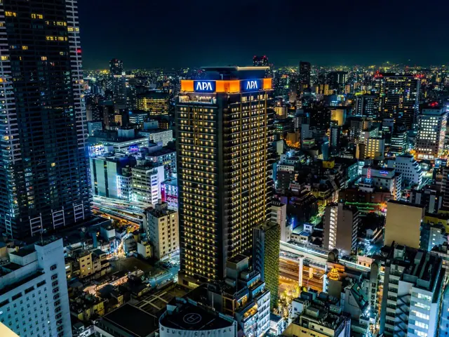 APA Hotel & Resort Osaka Umeda Eki Tower illuminated against the Osaka skyline