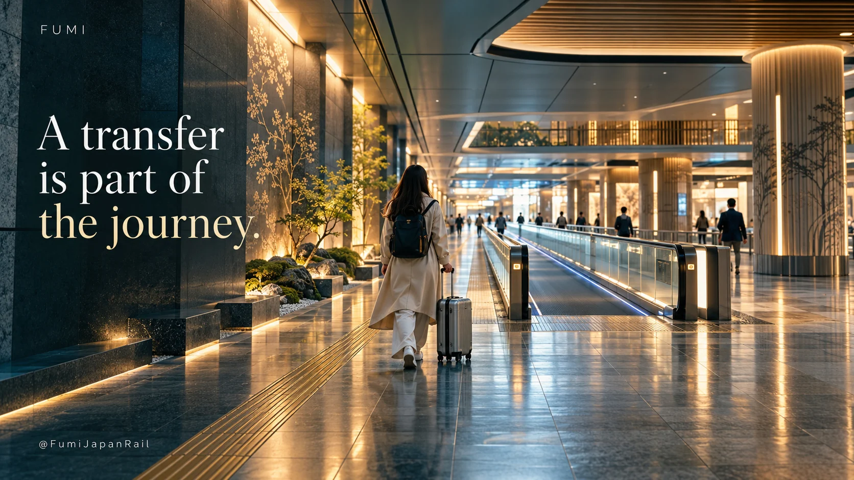 A traveller with luggage walks along a spacious station corridor. A transfer is part of the journey.