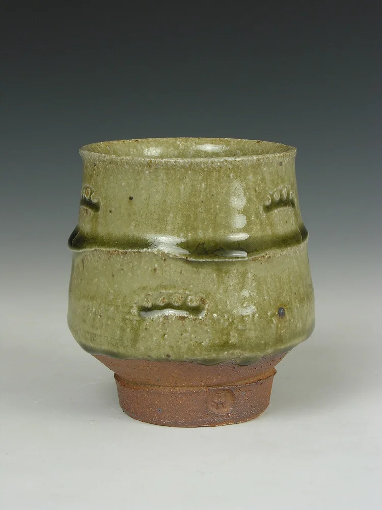A ceramic yunomi tea cup with an ash glaze